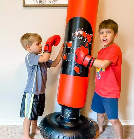 Two children using a free-standing punching bag at home