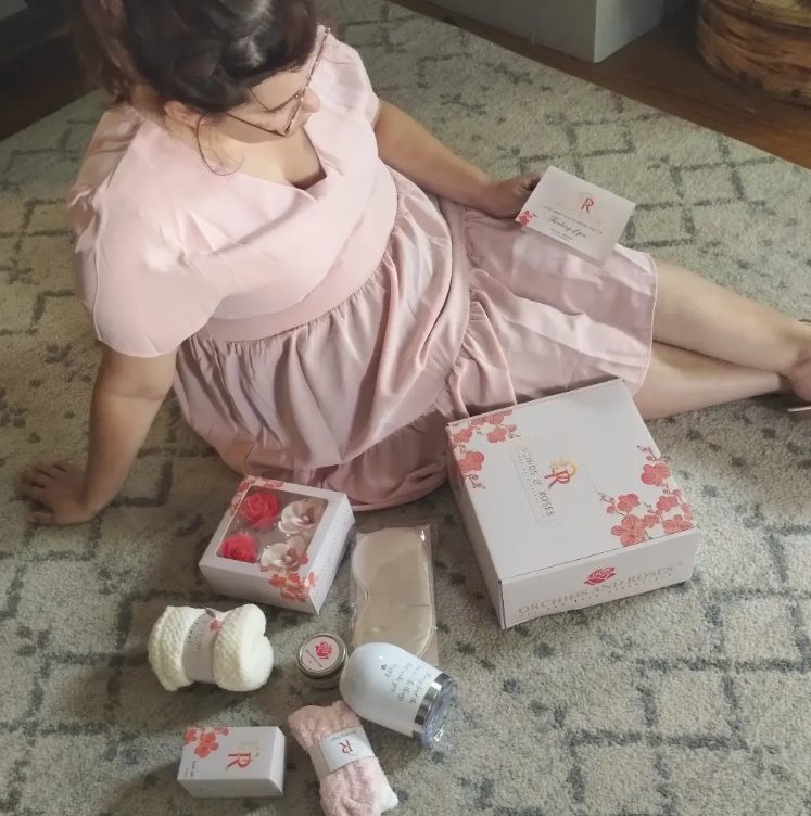 Creator seated beside a self-care gift set arranged on a rug